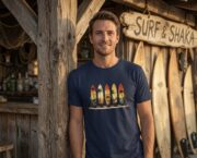 Man wearing a navy Retro Surf Rack T-shirt beside a wooden surf shack.