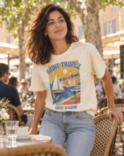 Woman wearing the ivory Saint-Tropez Côte d'Azur tee on a shaded café terrace in Saint-Tropez