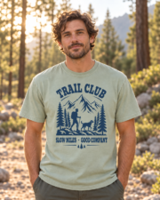 Man wearing the Bay Trail Club tee, front view showing the navy mountain, hiker and dog graphic on a forest trail.