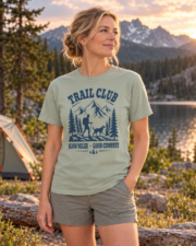 Woman wearing the Bay Trail Club tee in a three-quarter view beside a mountain lake and campsite.