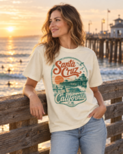 Woman wearing an ivory Santa Cruz California surf T-shirt by the pier railing