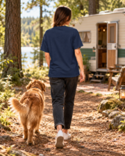 Back view of a woman wearing the plain True Navy camping tee beside a caravan and dog