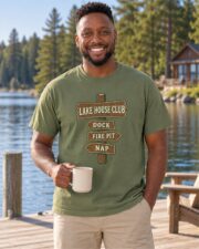 Man wearing the Moss Lake House Club Signpost T-shirt on a wooden dock with a coffee mug