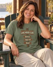 Woman in the Moss Lake House Club Signpost T-shirt relaxing in an Adirondack chair on a cabin porch