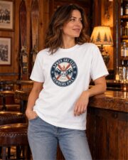 Woman in the White Après Ski Club Crest T-shirt leaning on the bar of an old ski club lounge