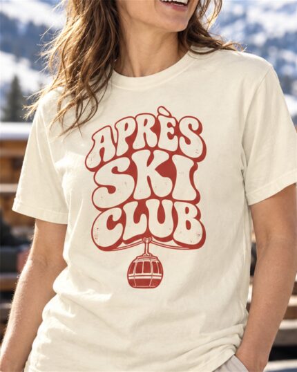 Woman wearing the Ivory Après Ski Club Retro T-shirt on a sunny ski lodge terrace