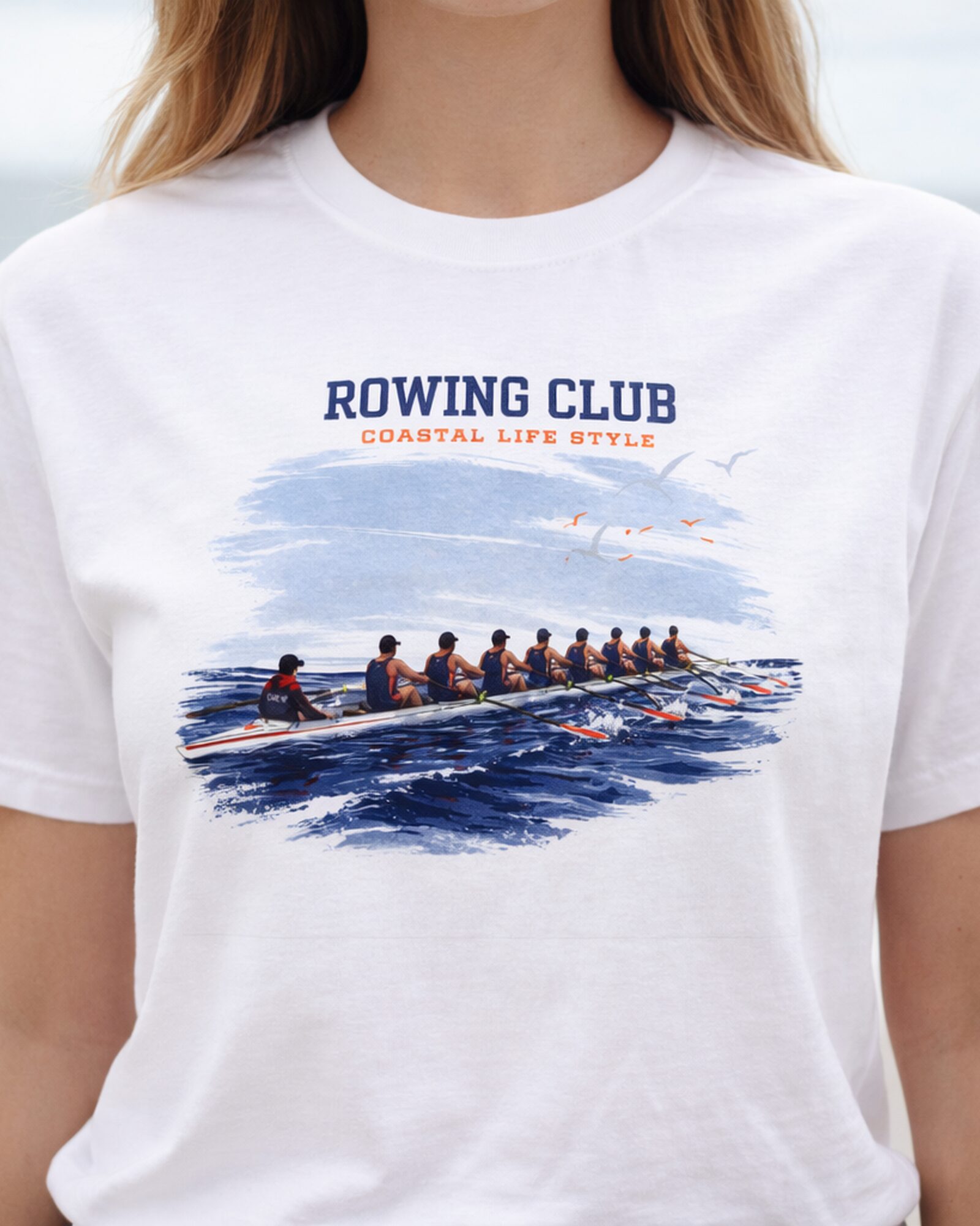 Rowing Club coastal T-shirt – female lifestyle close-up Close-up of a woman wearing the white Rowing Club coastal T-shirt by the water.