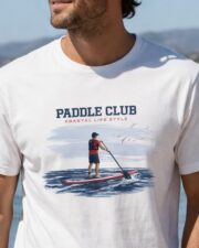 Close-up of a man wearing the white Paddle Club coastal T-shirt by the sea.