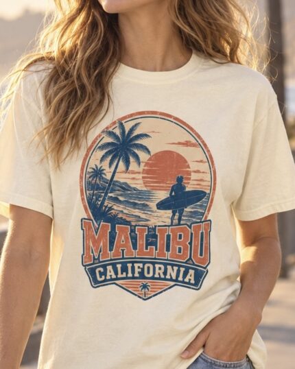 Woman wearing the ivory Malibu California Surf Tee on a Malibu beachfront promenade at sunset