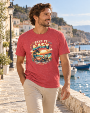 Man wearing the Heather Red Take it Easy T-Shirt while walking beside a harbor.