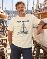 Man wearing the Anatomy of a Sailboat T-shirt beside a classic wooden sailboat