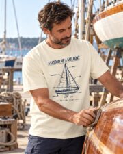 Man in the Anatomy of a Sailboat T-shirt sanding a wooden boat hull