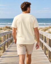 Back view of a man wearing the Ivory Beneath the Blue T-shirt on a boardwalk