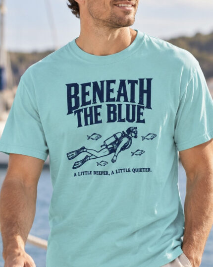 Man wearing the Lagoon Blue Beneath the Blue Scuba Diver T-shirt by the harbor